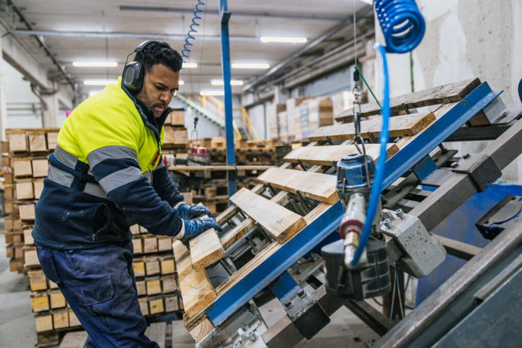 Factory worker assembling wooden pallets in recycling plant
